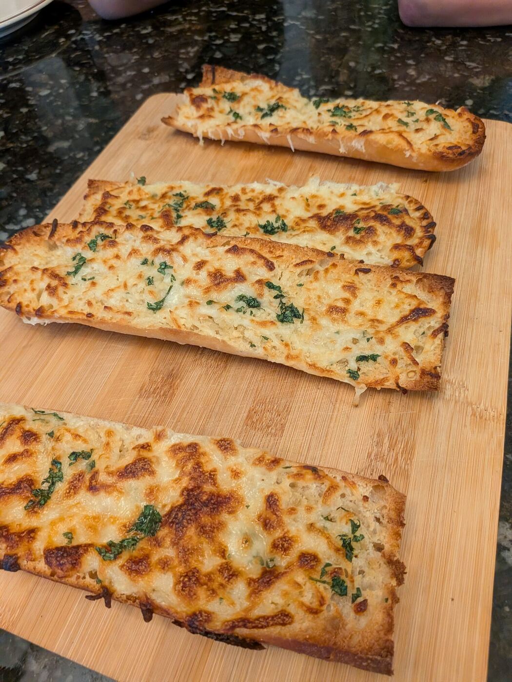 Cheesy garlic bread with herbs on a wooden board