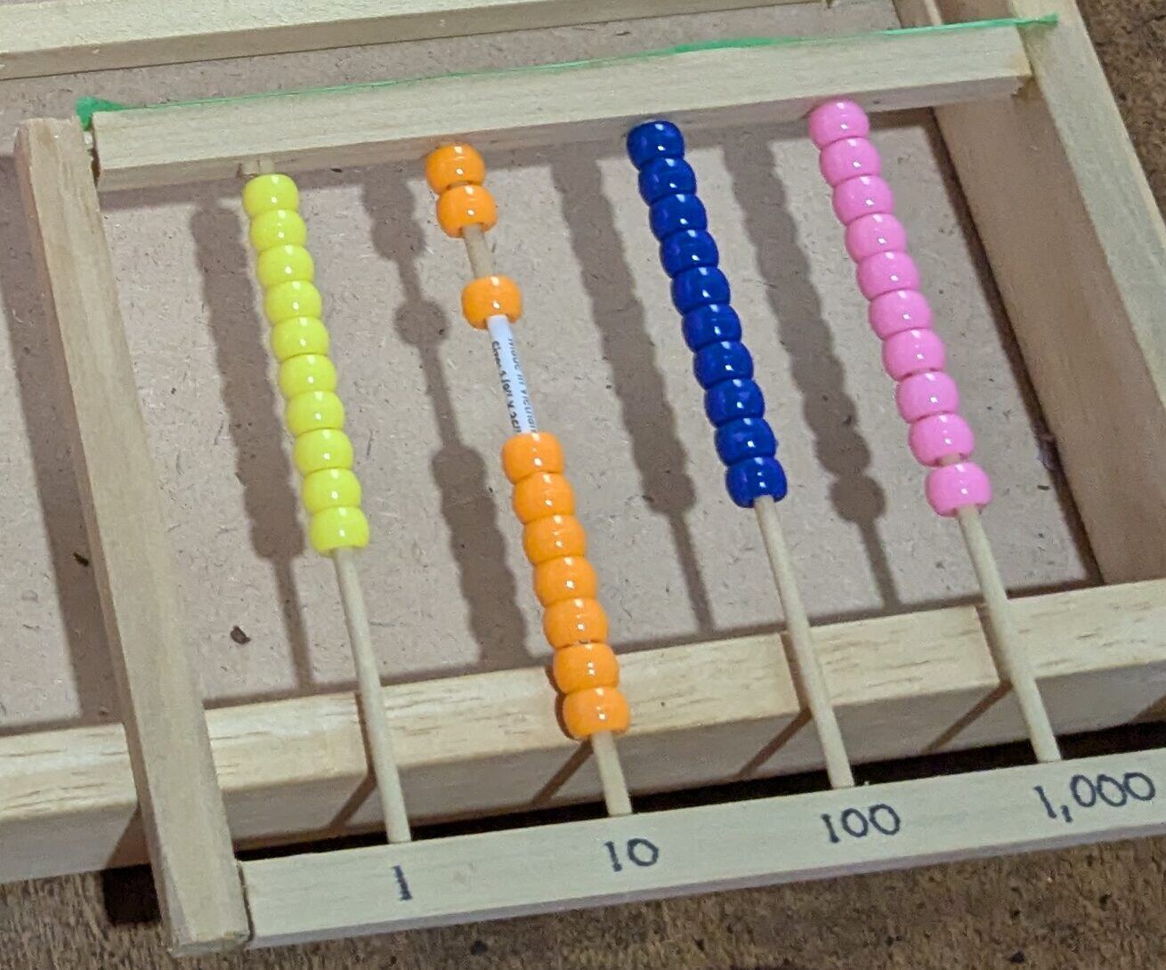 A handmade abacus with rows of colored beads for ones, tens, hundreds and thousands