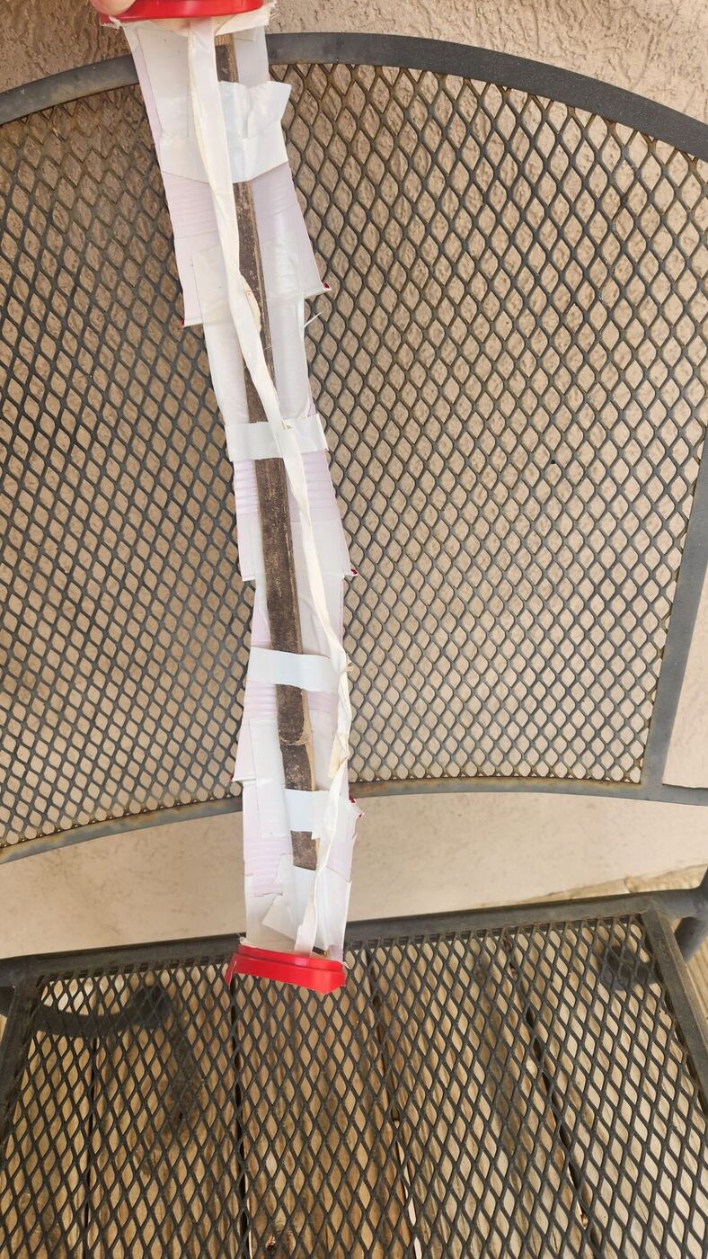 A homemade instrument, a long tube wrapped in tape, hanging over a patio chair