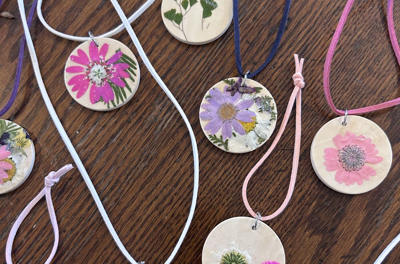 Friendship necklaces, each a wooden disc with a pressed flower, on colored cords