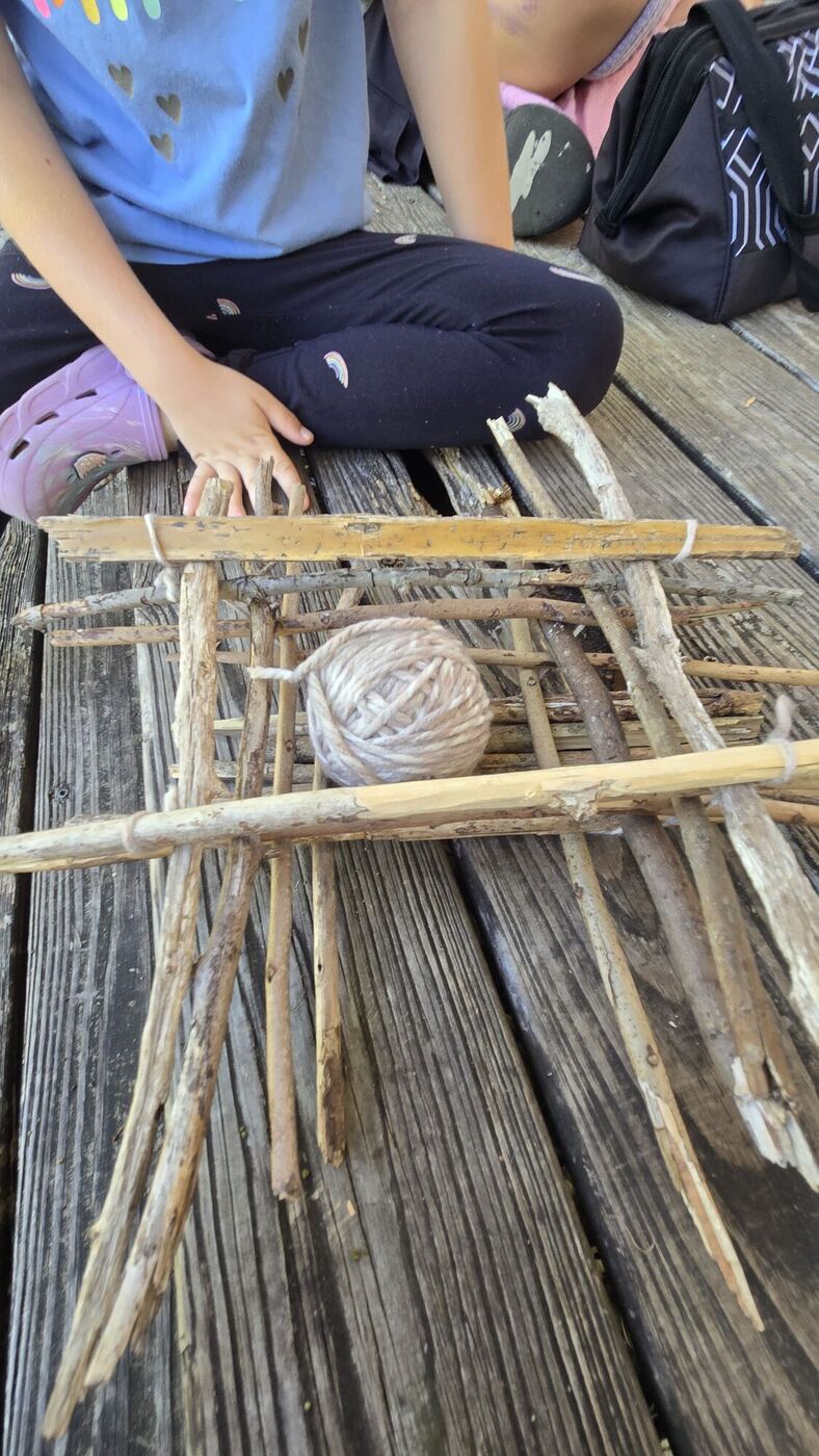 A basket of sticks tied with string, a ball of yarn inside