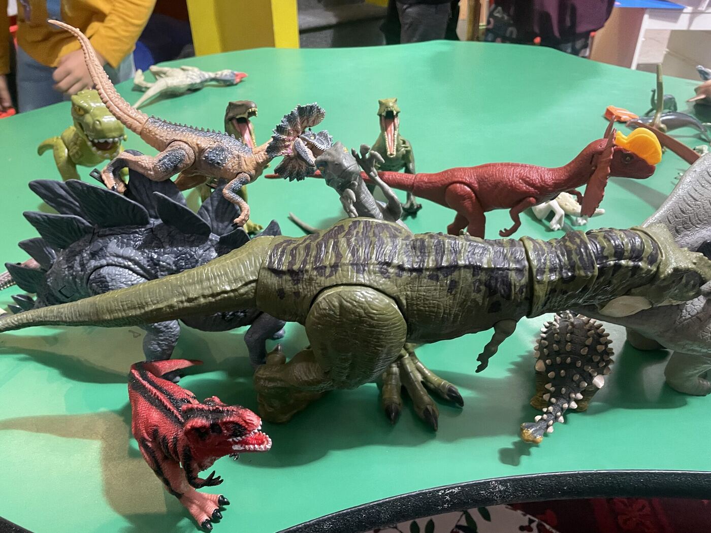 Donated toy dinosaurs gathered on a green table