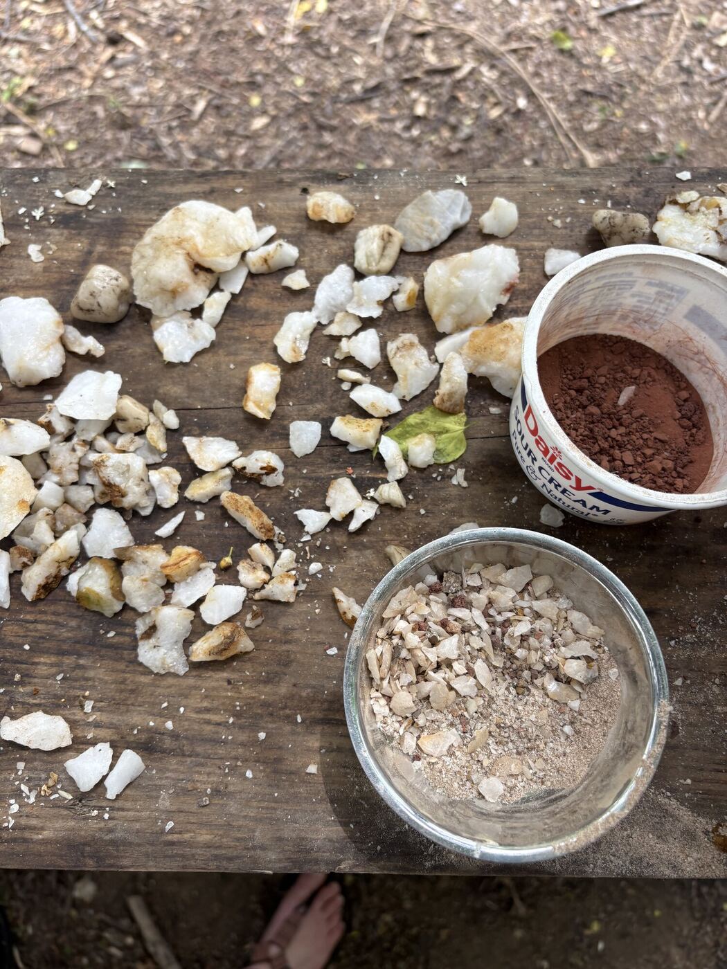 Chiseled pieces of quartz laid out on the table, a bowl of polished chips beside them