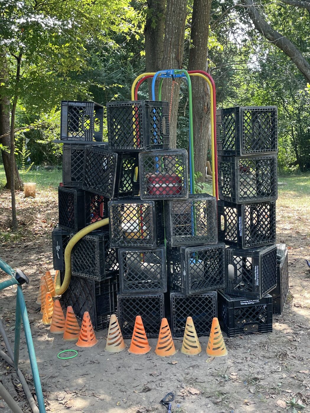 A tower of milk crates, colored hoops and cones under the trees in the play yard