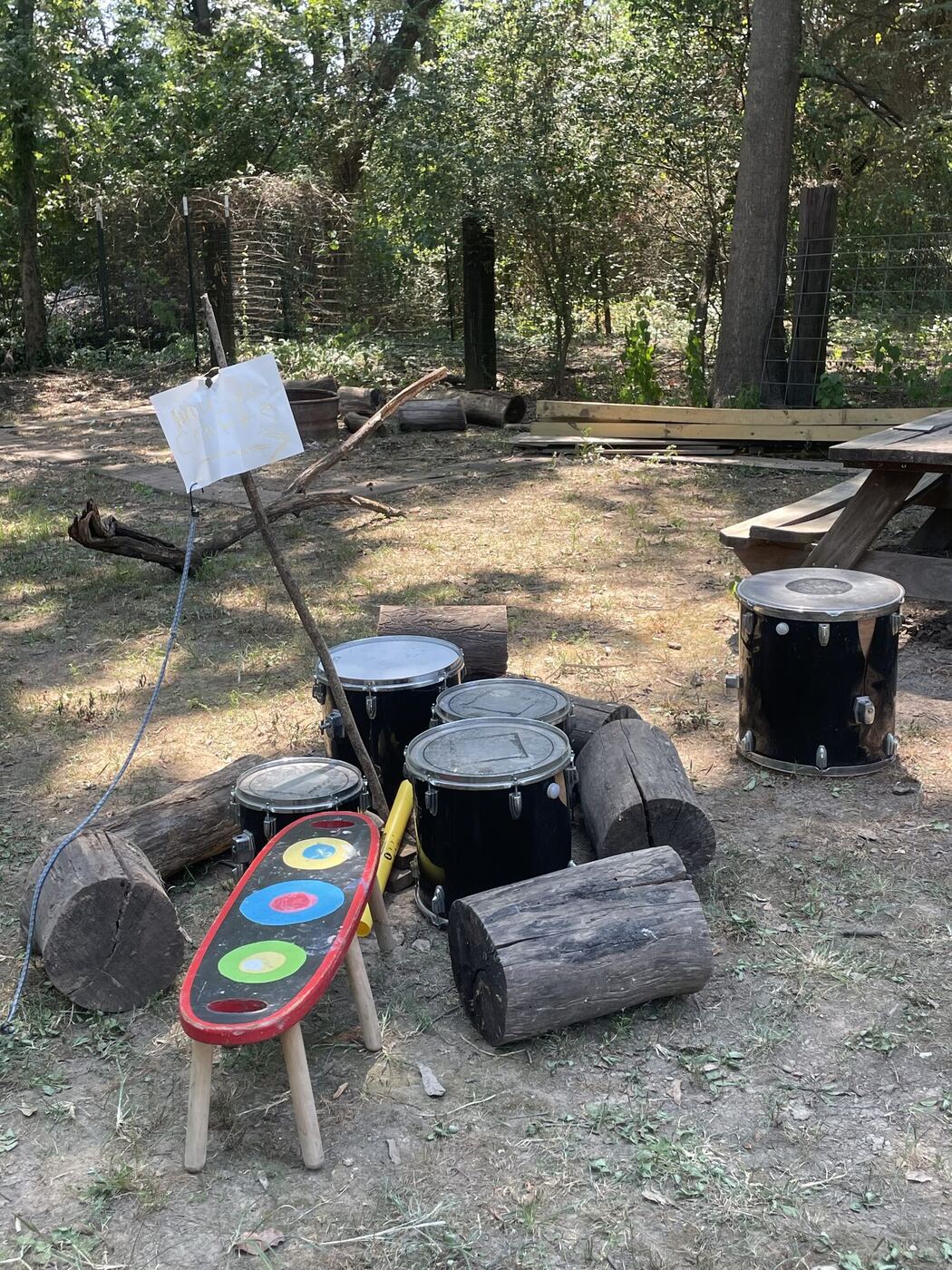 Drums, logs and a painted stool set out in the play yard as a music area