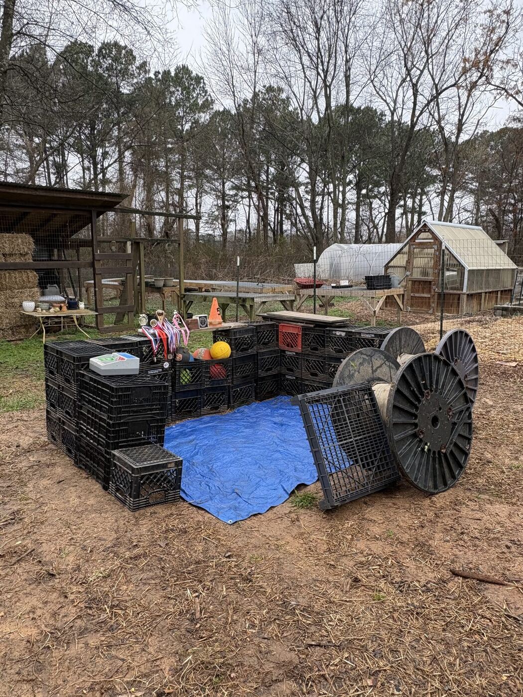 A shop built of milk crates, cable spools and a blue tarp in the play yard