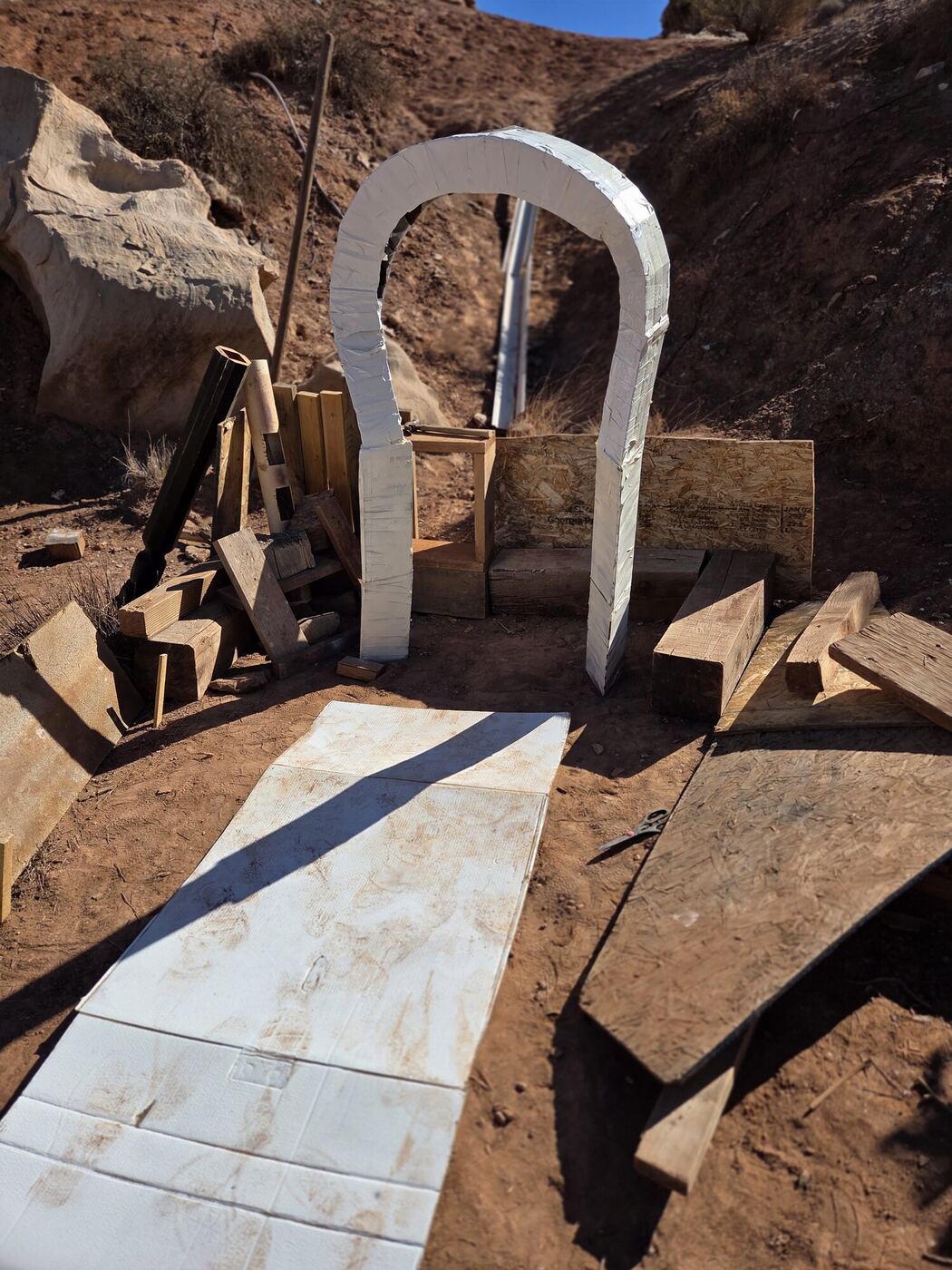 A white arch and plank path built into the red hillside for the haunted path