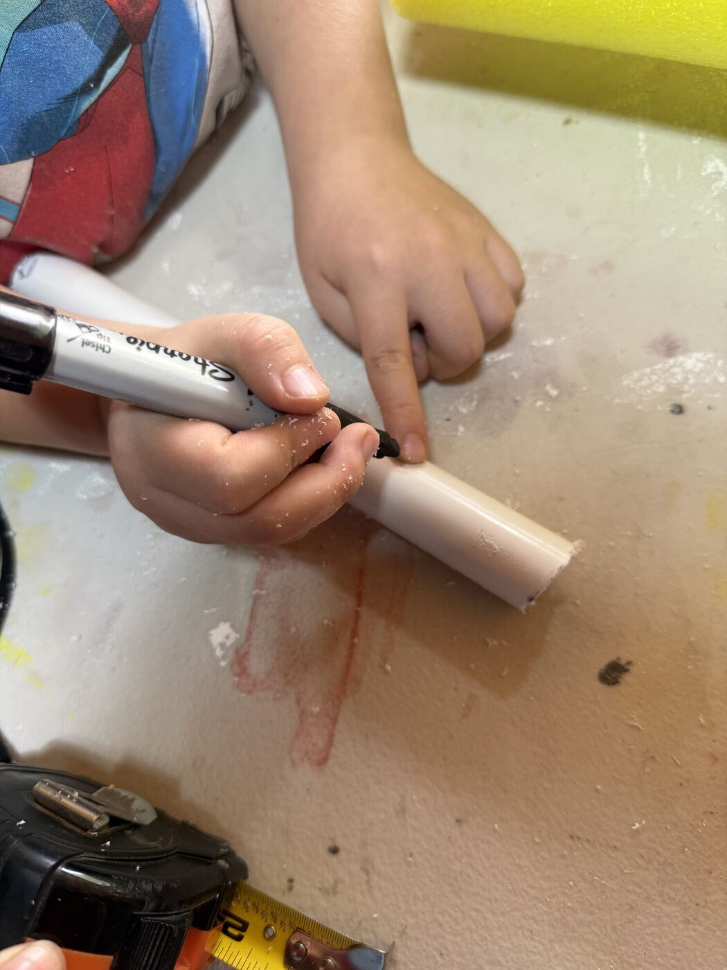 Hands marking a short piece of pipe with a marker