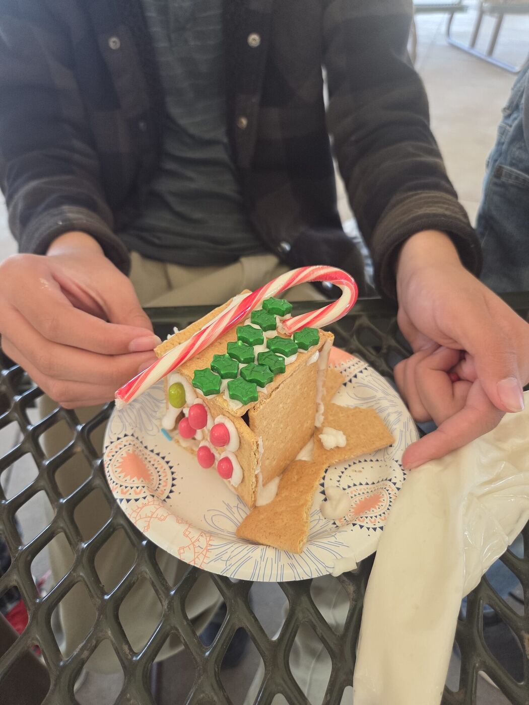 A gingerbread house held up on a paper plate