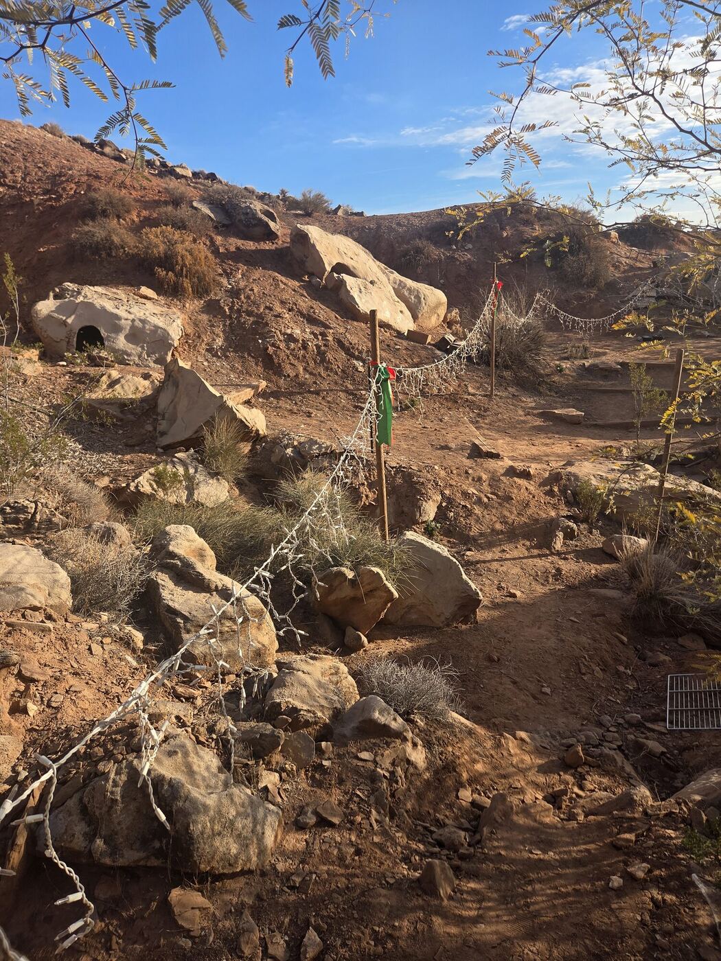 Strings of lights on stakes running along a rocky path up a slope