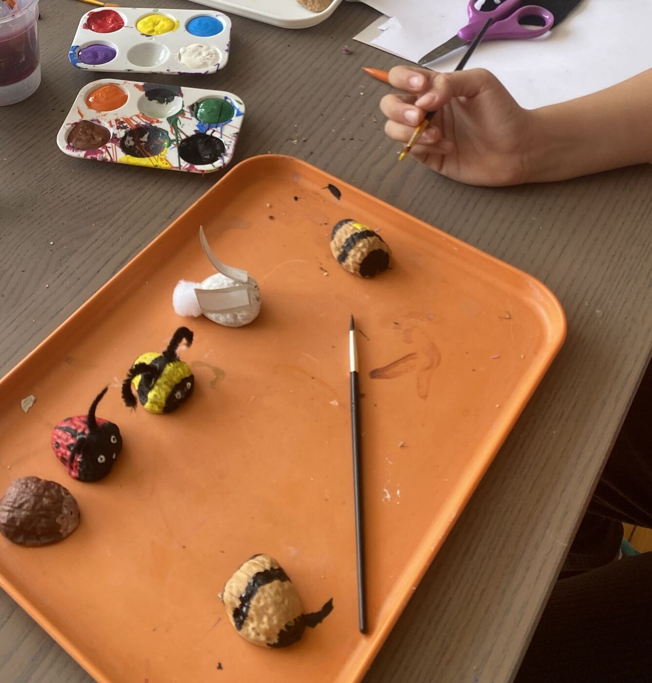 Painted rock bugs drying on an orange tray