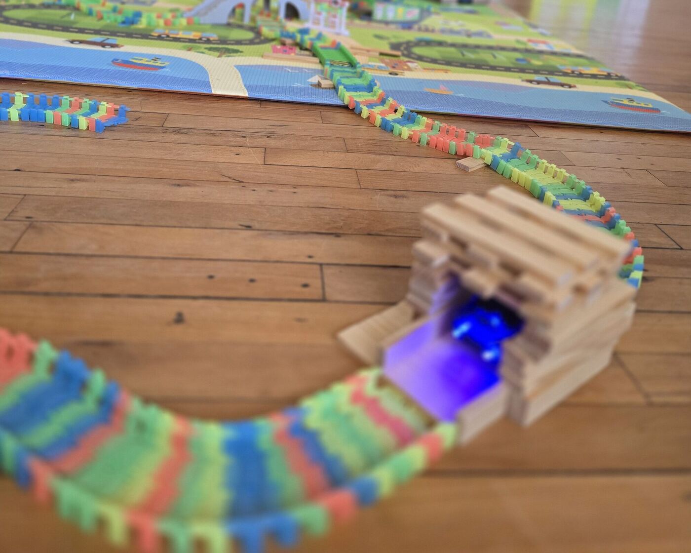 A toy car track running through a tunnel built from wooden planks