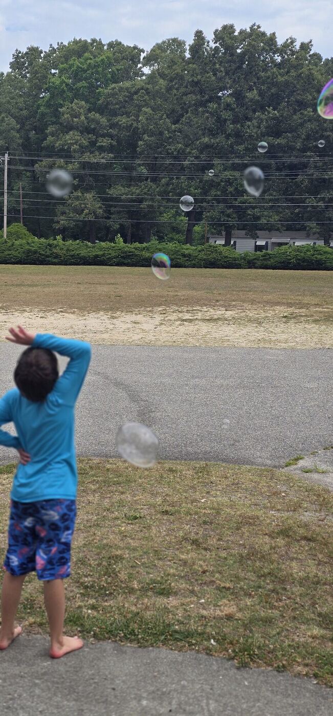 A learner from behind watching bubbles float over the field