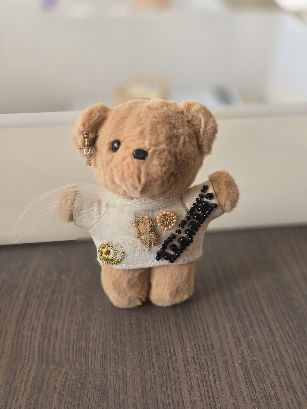 A mended teddy bear standing in a sewn shirt with buttons