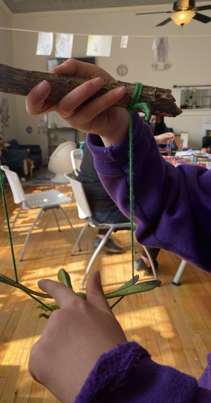 A toy grasshopper hanging on green yarn from a stick, worked like a puppet